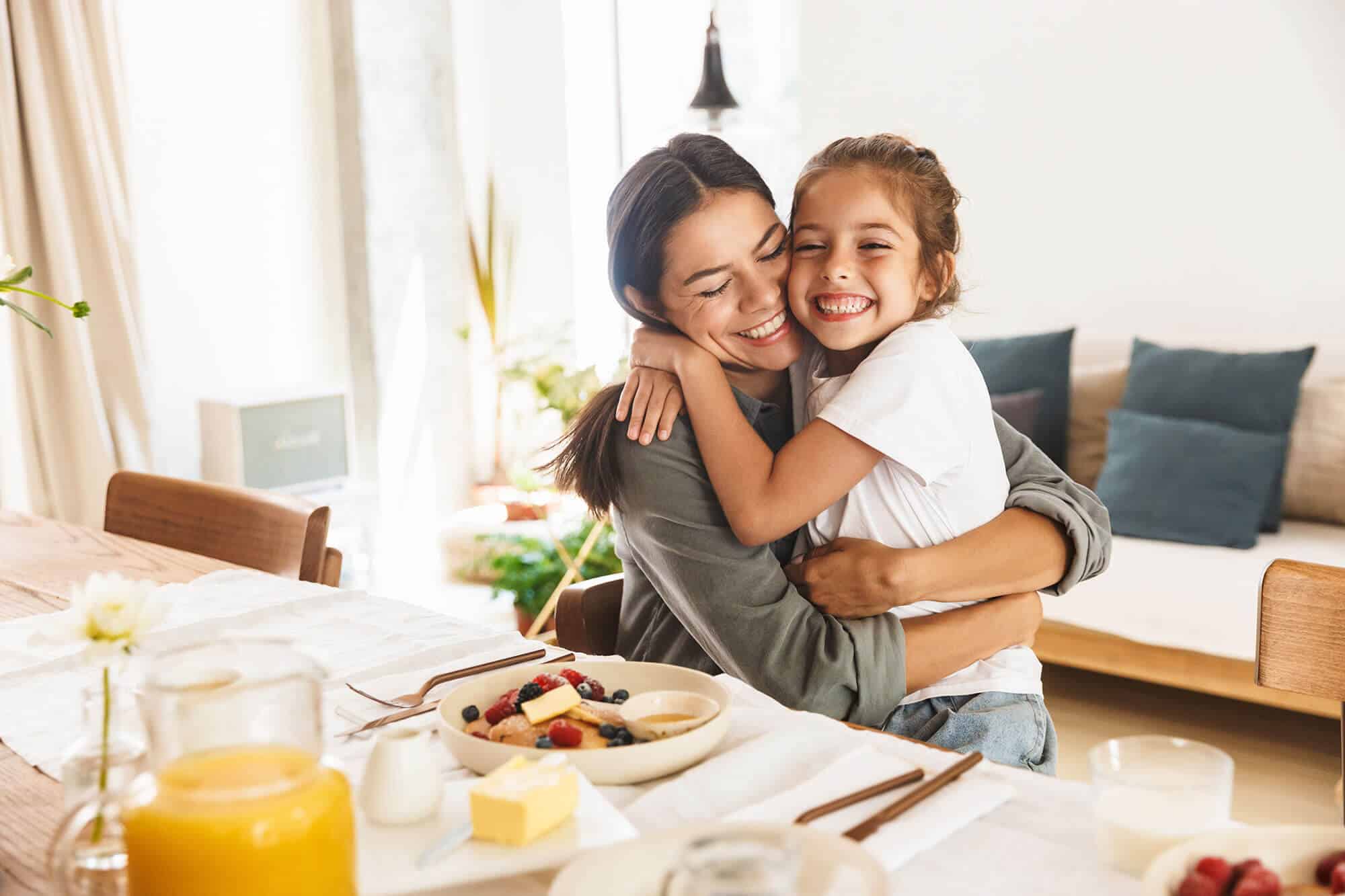 Mother and daughter hug while enjoying breakfast